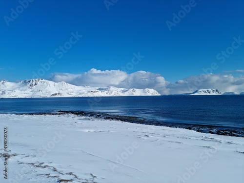 sunny blue sky and sea with white snowy mountains on the island of mageroya in north cape county