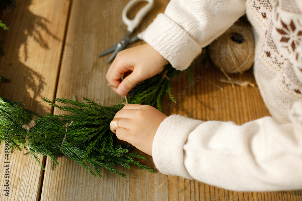 girl making cedar wreath on wooden craft table. child tying a knot. girl making cedar wreath on wooden craft table. child tying a knot.