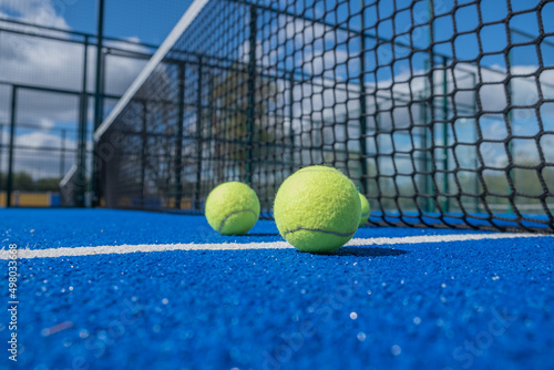 balls next to the net and the center line of a blue paddle tennis court © Vic