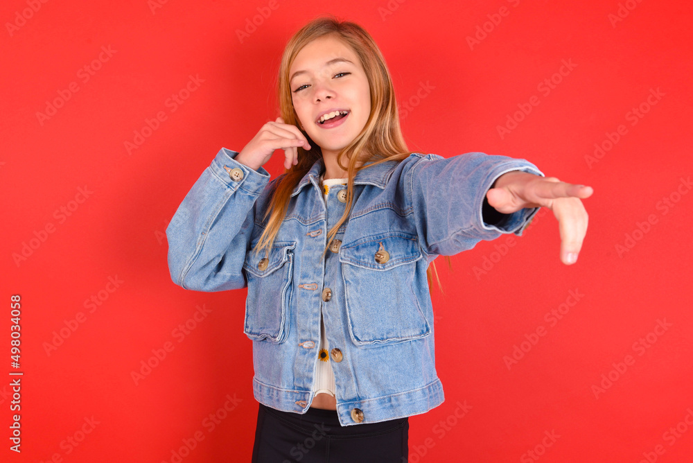 blonde little kid girl wearing denim jacket over red background smiling cheerfully and pointing to camera while making a call you later gesture, talking on phone blonde little kid girl wearing denim jacket over red background smiling cheerfully and pointing to camera while making a call you later gesture, talking on phone
