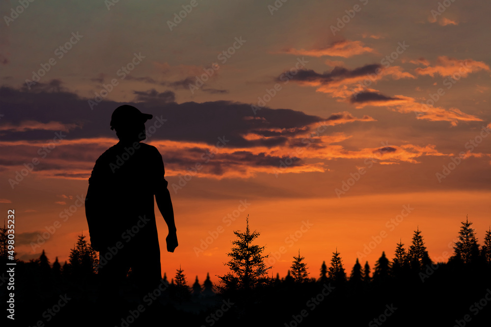 Traveler man's silhouette facing mountain at golden hour, silhouette man standing on outdoors in twilight on evening the last light of a day.