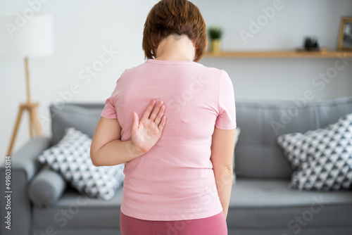 Pain between the shoulder blades, woman suffering from backache at home