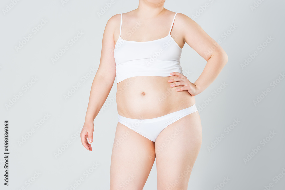 Woman with fat abdomen, overweight female body on gray background