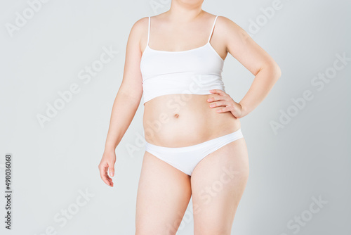 Woman with fat abdomen, overweight female body on gray background