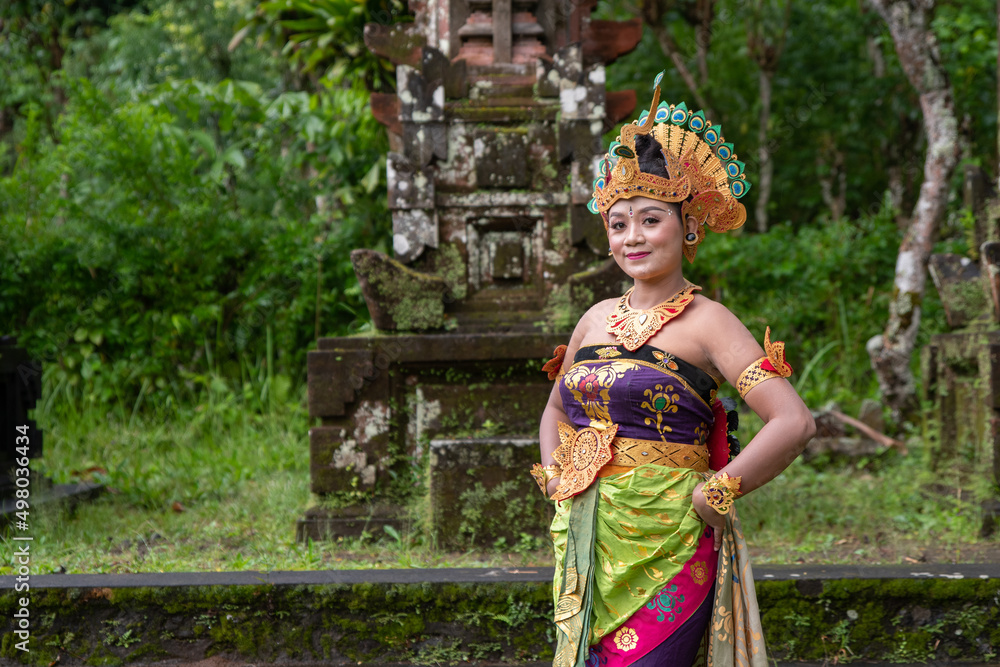 Portrait Balinese dancer woman at old temple with traditional peacock costume Portrait Balinese dancer woman at old temple with traditional peacock costume