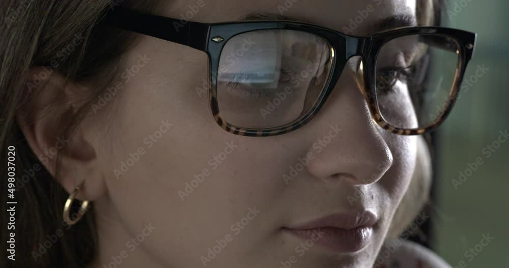 Young woman looking at computer screen with eyeglasses Young woman looking at computer screen with eyeglasses