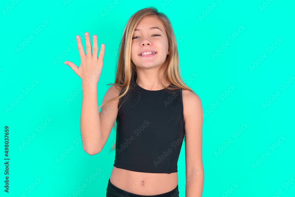 blonde little kid girl wearing black sport clothes over green background smiling and looking friendly, showing number five or fifth with hand forward, counting down blonde little kid girl wearing black sport clothes over green background smiling and looking friendly, showing number five or fifth with hand forward, counting down