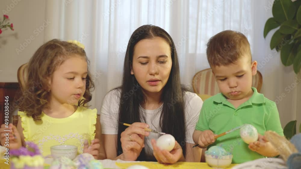 beautiful family, mother and kids painting easter eggs together. Sister and brother painting with brush. Family time. beautiful family, mother and kids painting easter eggs together. Sister and brother painting with brush. Family time.