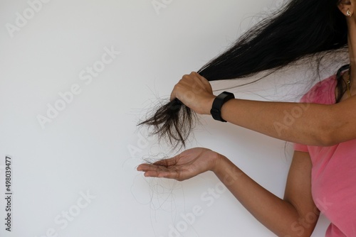 A woman showing excessive hair fall, hair loss, damage, dandruff, pollution, thin, grey hair in a white background. Hair transplantation, protein deficiency, sleep, nutrition, oil, condition, shampoo.