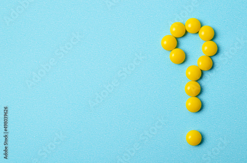 Pills yellow as a question mark on blue background with copy space
