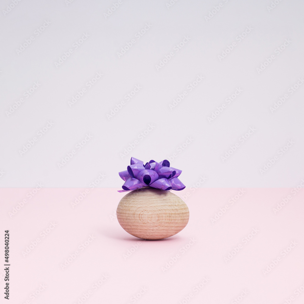 Easter egg with festive purple bow isolated on pastel background. Holiday concept. Copy space. Easter egg with festive purple bow isolated on pastel background. Holiday concept. Copy space.