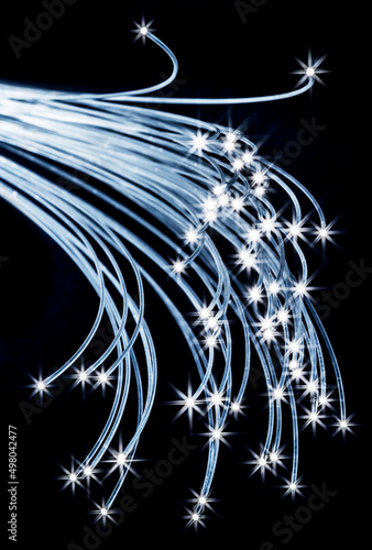 Bundle of optical fibers with lights in the ends. Black background.