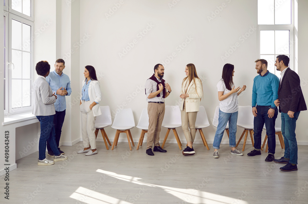 Fototapeta premium Different groups of colleagues communicate with each other during work break in coworking office. Multiracial stylish casual women and men work with each other in comfortable and positive atmosphere.