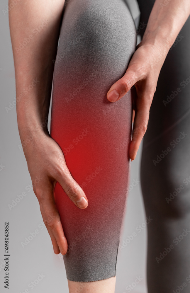 Shin splints. Woman suffering from pain in leg with red spot closeup