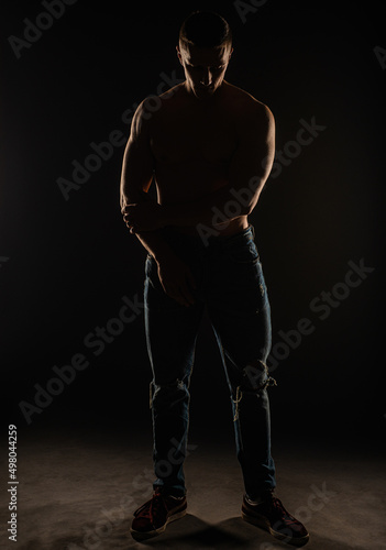 Perfect silhouette of a guy posing in studio while standing and being topless