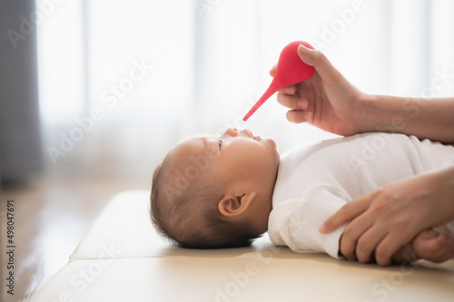 Canvas Print mother cleaning the nose of a newborn baby with nasal aspirator or syringe ball