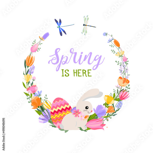 Easter spring greeting card. A wreath of spring flowers and herbs with bright Easter eggs  a cute bunny and dragonflies. Inscription Spring is here.