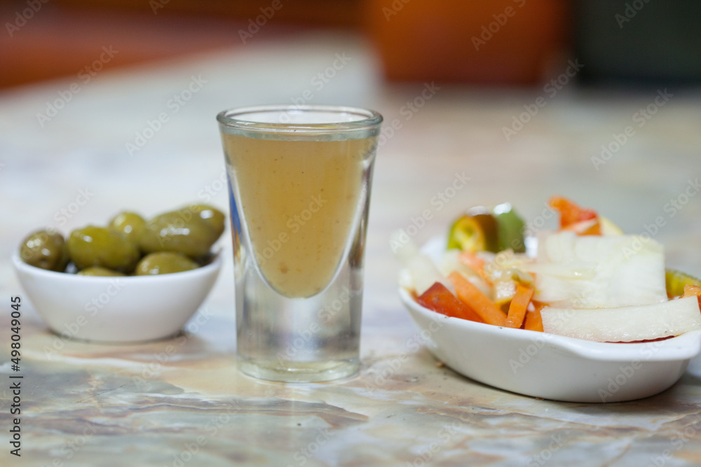 ginger shot served with olives and vegetable salad ginger shot served with olives and vegetable salad