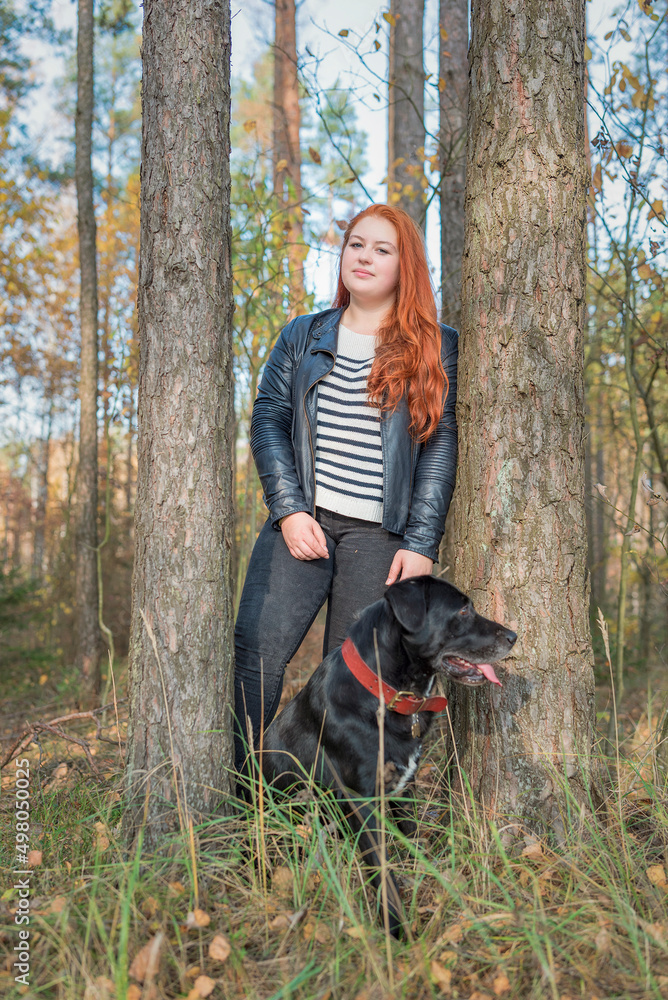 Portrait of a young beautiful red-haired girl in the forest.