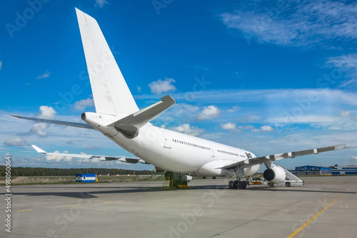 Large white aircraft parked at the airport, view of the tail.