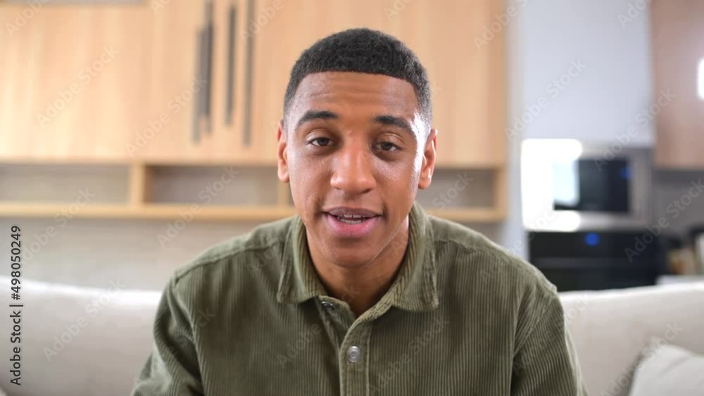 Portrait of happy young multiracial guy sitting at desk and waving at camera. Smiling man in casual shirt involved virtual meeting. Hispanic male student taking a part in educational conference Portrait of happy young multiracial guy sitting at desk and waving at camera. Smiling man in casual shirt involved virtual meeting. Hispanic male student taking a part in educational conference