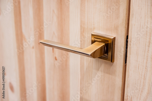 Door handle made of copper close-up. The design of a wooden interior or entrance door