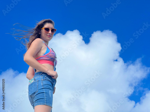 Portrait of confident strong young woman. Clouds and sky in the background. Empty space for text