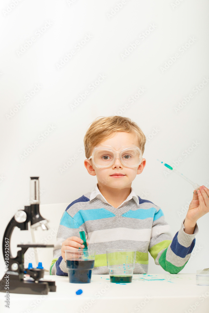 Boy five years old, experimenting with colored liquids. Chemical experiments of a little scientist boy of European appearance. Boy five years old, experimenting with colored liquids. Chemical experiments of a little scientist boy of European appearance.