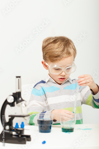 Boy five years old, experimenting with colored liquids. Chemical experiments of a little scientist boy of European appearance.
