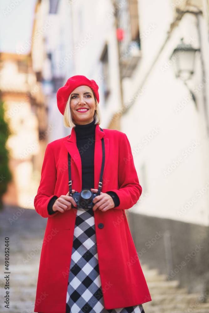 Smiling female tourist with photo camera standing on stairs on city street