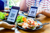 Smartphone in hand to scan QR code payment tag with blurry Thai  Shrimp Salad and dessert in restaurant to accepted generate digital pay without money. Qr code payment concept.
