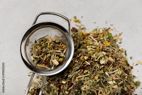 Dry herbal tea in a strainer for brewing on a gray cement background.Collection of useful herbs.Top view.Children and immunity tea.Copy space. Place for text.