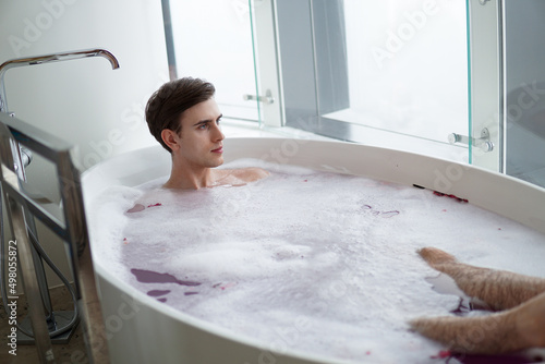 Young handsome man enjoying in the bathtub.