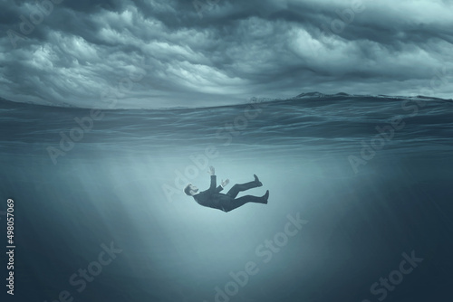 The human body sinks in gray water, sinks to the bottom, gray clouds. Depression, procrastination, despair, fear, apathy. photo