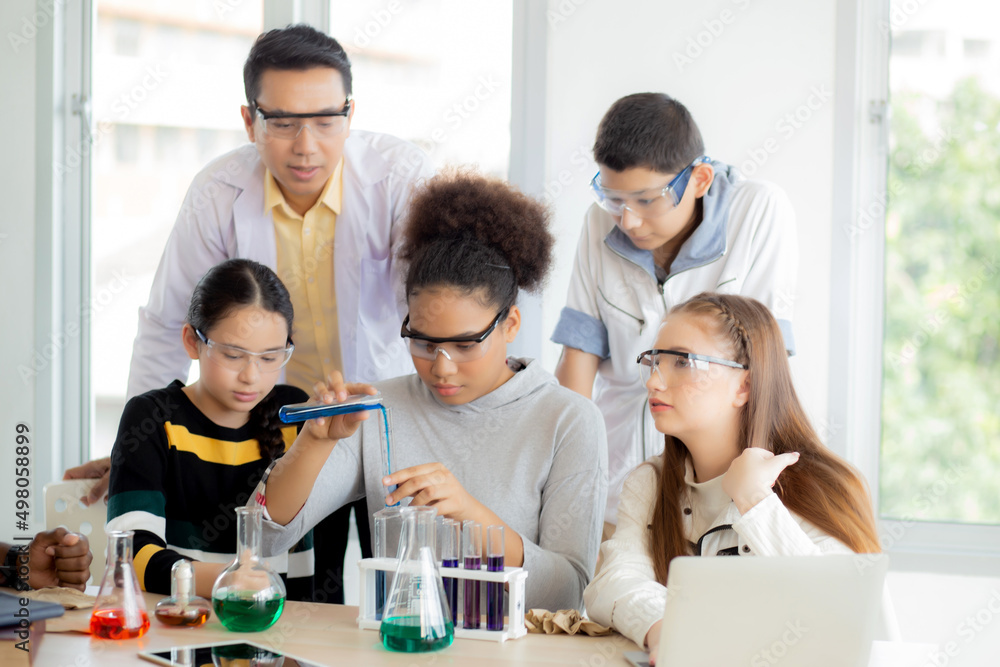 Young teacher teaching group student about science and test chemical for liquid in the lab of school, children studying and learning experiment science in the laboratory, education concept. Young teacher teaching group student about science and test chemical for liquid in the lab of school, children studying and learning experiment science in the laboratory, education concept.