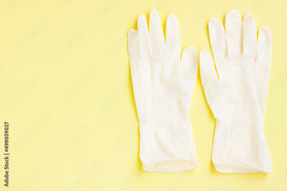 Obraz premium White latex protective gloves on yellow background