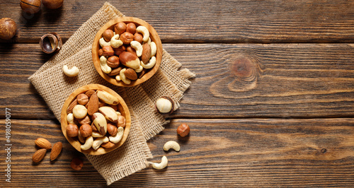 Various nuts in bowl - cashew, hazelnuts, almonds, brazilian nuts and macadamia on a wooden background. Top view with copy space.