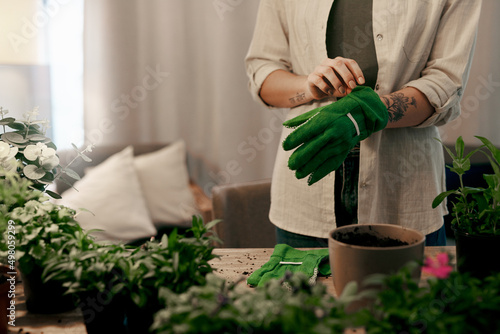 Its time to get my hands dirty. Cropped shot of an unrecognizable florist potting plants inside her store.