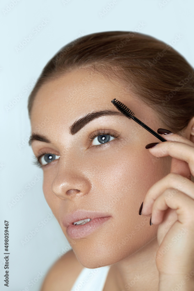 Eyebrow makeup.  Beauty model shaping brows with brush eyebrow closeup . Beautiful sexy woman with professional makeup contouring eyebrows