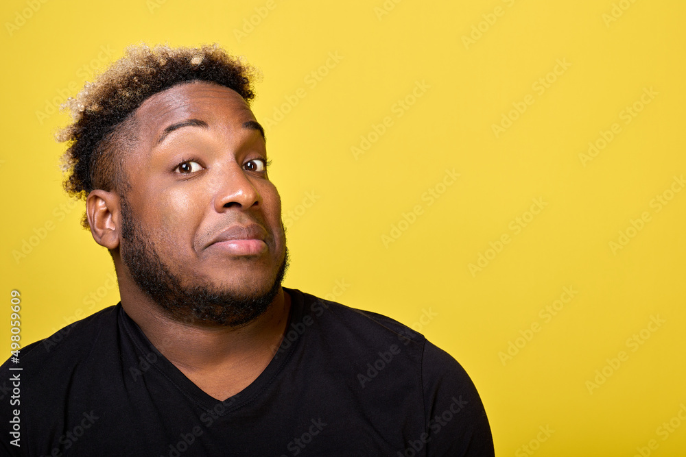A dark-skinned, handsome unshaven man with curly hair looks into the camera lens with a surprised look. A young man in casual clothes looks questioningly at the photographer A dark-skinned, handsome unshaven man with curly hair looks into the camera lens with a surprised look. A young man in casual clothes looks questioningly at the photographer