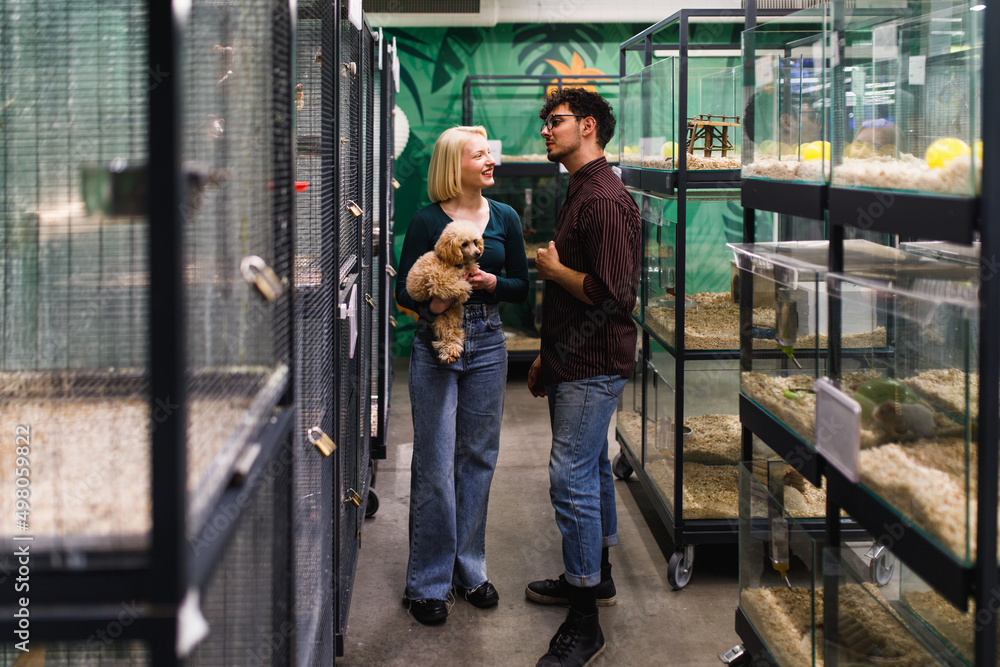 Φωτογραφία Happy couple with their poodle puppy buying in pet shop new pet.