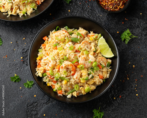 Prawn fried rice with eggs and vegetables in black bowl. Healthy asian food.