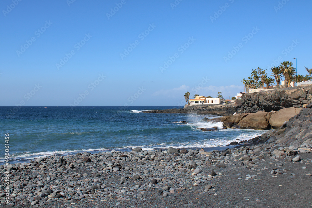 Seashore of a village La Caleta in Tenerife, Canary Islands, Spain, sunny day, pebble beach and ocean waves