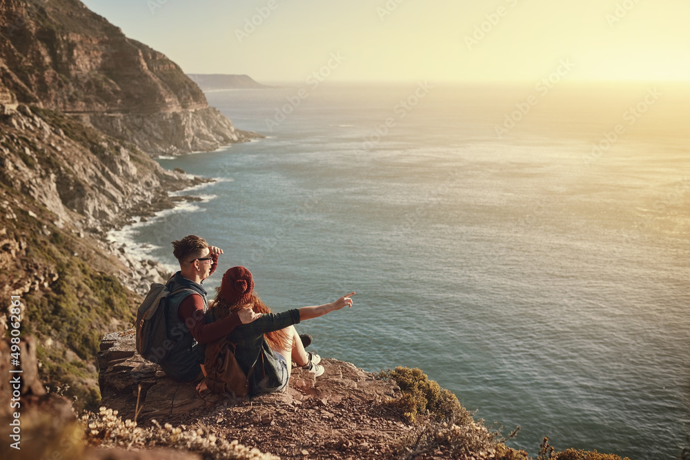 Take a look over there. High angle shot of an affectionate young couple taking in the view from a mountaintop.