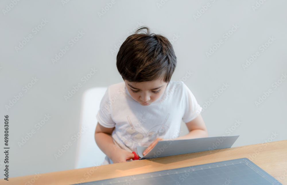 Kid using scissors cutting cardboard , Schoolboy making art and craft for his homework,Child learning how to use the scissors cut the paper,Children learn and play at home, Home school concept Kid using scissors cutting cardboard , Schoolboy making art and craft for his homework,Child learning how to use the scissors cut the paper,Children learn and play at home, Home school concept