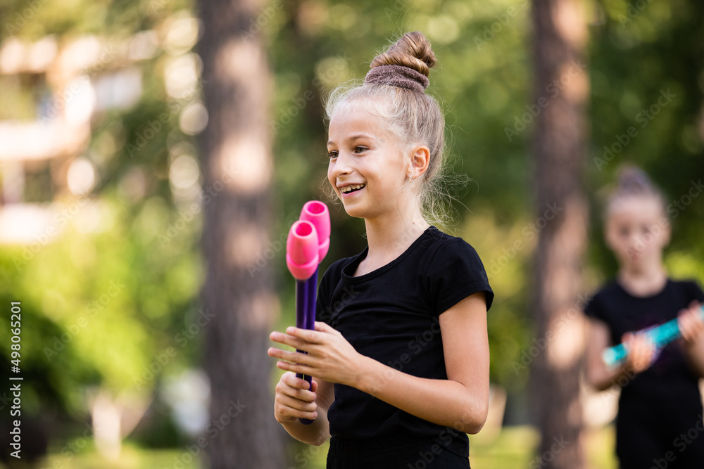 Portrait of joyful girl on rhythmic gymnastics training with clubs in summer in sports camp outdoors Portrait of joyful girl on rhythmic gymnastics training with clubs in summer in sports camp outdoors