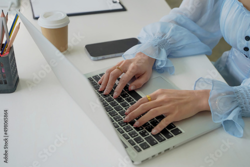business woman sitting in office analyzing profit Market trends with tablet and paper reports placed on the table. , Asian business concept,focus on the right hand
