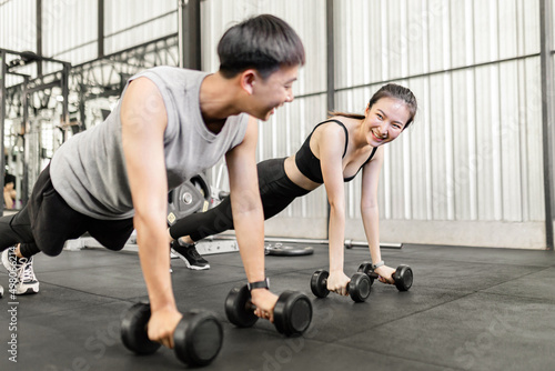 exercise concept The female and male members of the gym doing the basic renegade row posture with dumbbells while looing at each other’s face