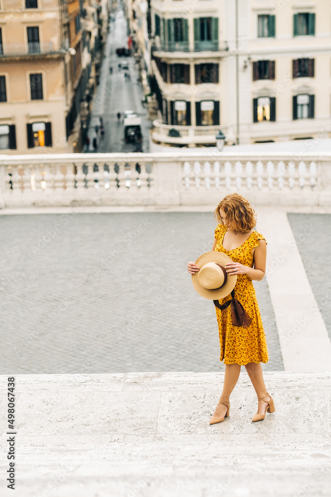 Italy summer tourism concept. Young woman in orange outfit stay overlooking Rome. 