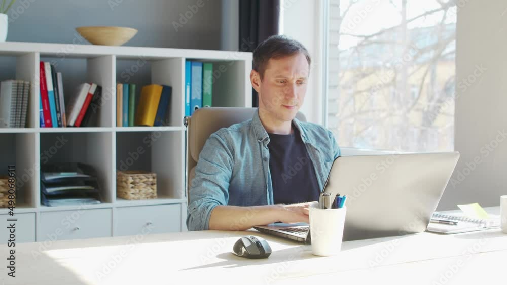 Young male entrepreneur works at home office at the computer. Workplace of freelancer or student. Remote work and education concept. Young male entrepreneur works at home office at the computer. Workplace of freelancer or student. Remote work and education concept.